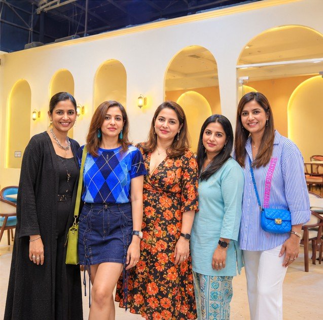 Five smiling friends posing together in the arched party hall at OWI Kids World