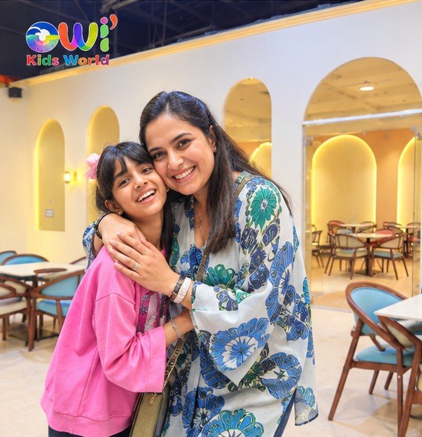 A mother and her daughter hugging and smiling in the arched party hall at OWI Kids World